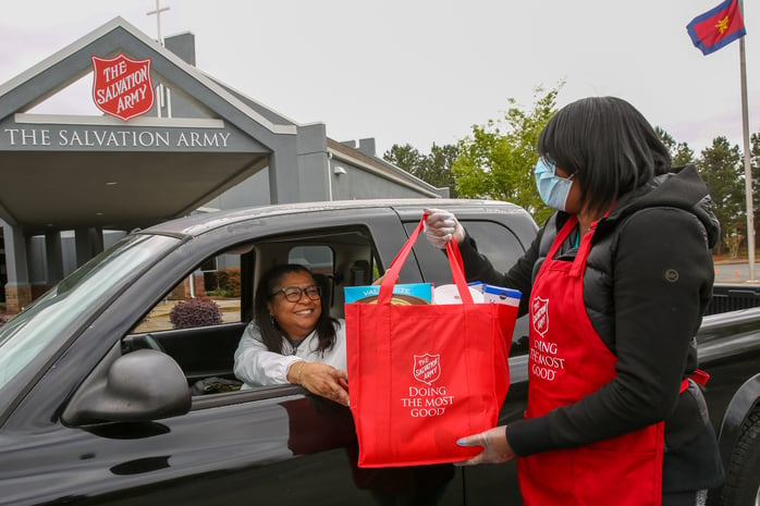 Volunteer distributing bags of food through the Gwinnett County Corps Drive-thru Food Pantry